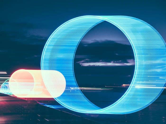 Digital composite image of illuminated ferris wheel against sky