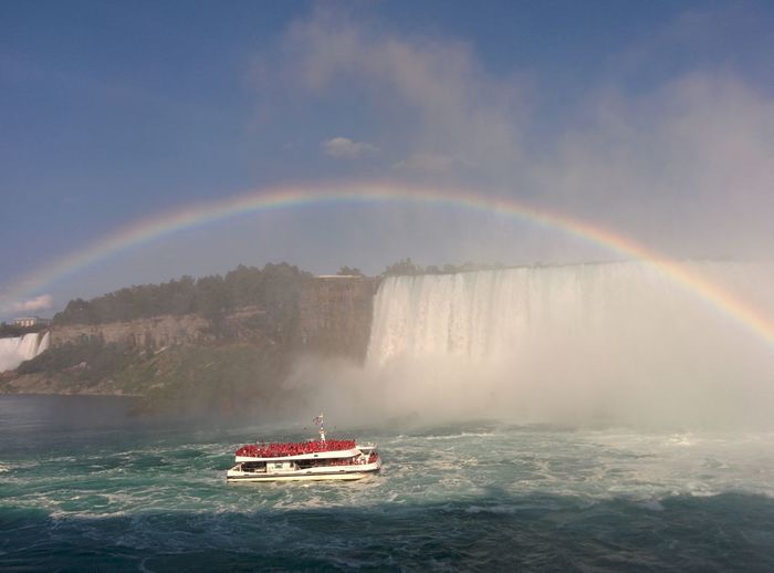 Scenic view of rainbow over ferry sailing at niagara falls
