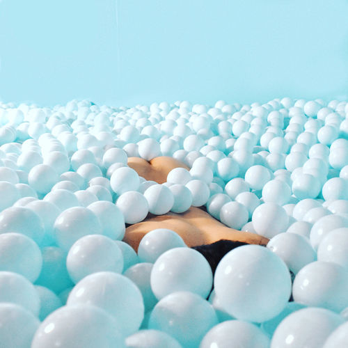 Close-up of naked person lying down in ball of pool