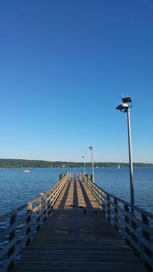 Pier over sea against clear blue sky