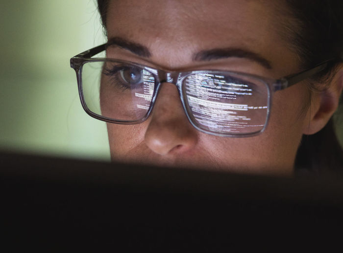 Computer programmer wearing eyeglasses looking at codes