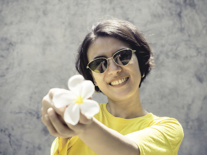 Portrait of smiling young woman holding flower