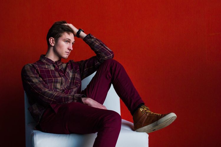 Man sitting on chair against red background
