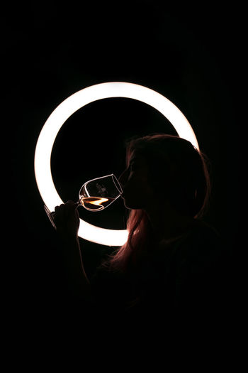 Close-up portrait of man holding illuminated lamp against black background
