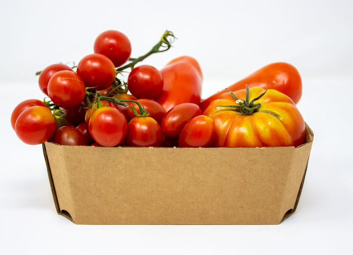 Close-up of tomatoes in box against white background