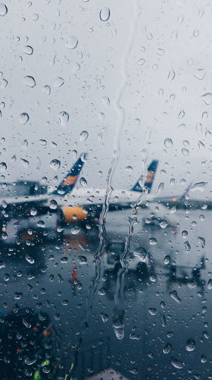 Water drops on window against planes at runway