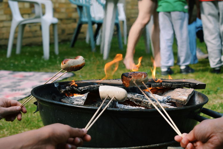 Close-up of people preparing food on barbecue grill