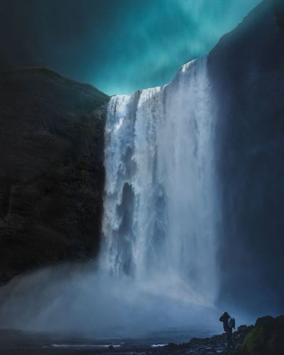 Scenic view of waterfall falling from mountain at night