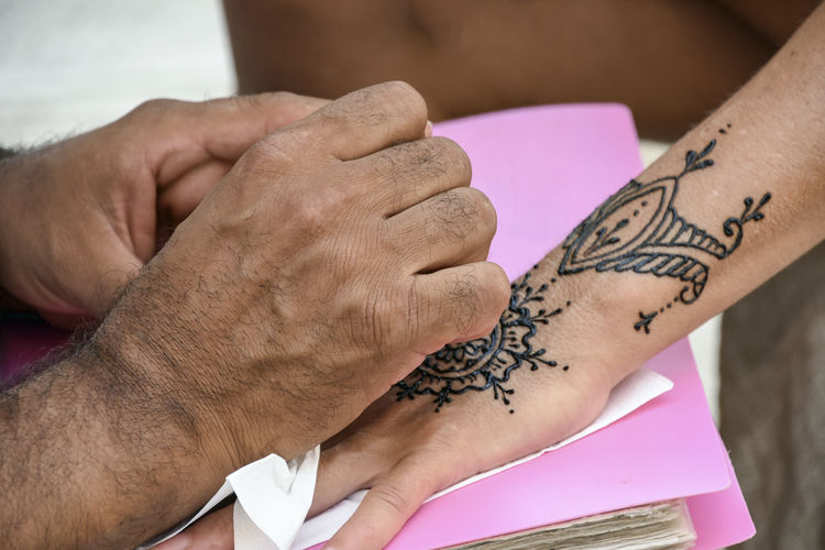 Drawing a temporary tattoo on the hand of a lady 
