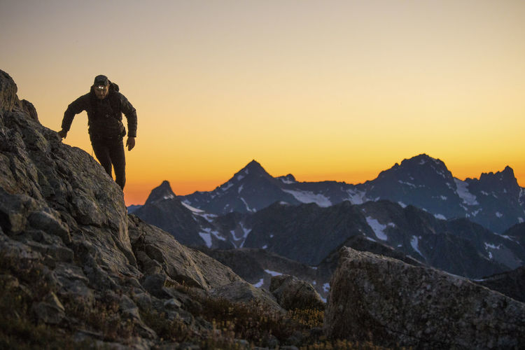 Hiker navigates a mountain route using headlamp after sunset.