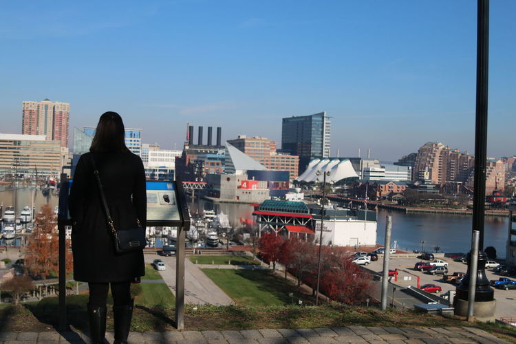 Rear view of woman standing by cityscape against clear sky