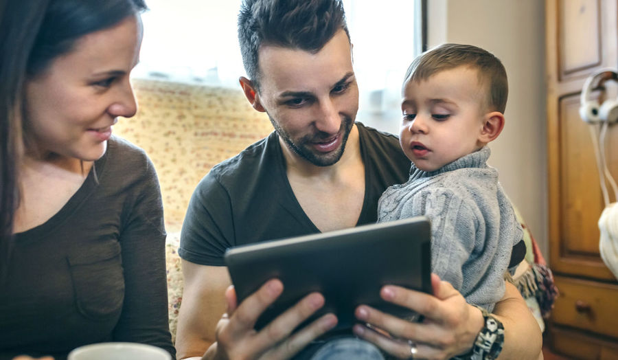 Parents with son using digital tablet while sitting in living room at home
