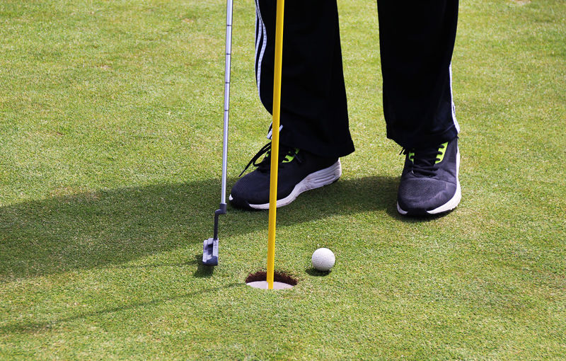 Low section of man playing golf at field