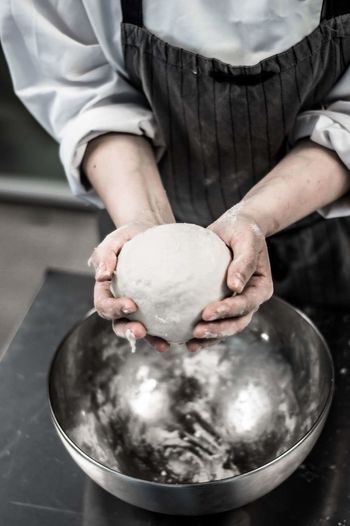 Midsection of chef kneading dough in kitchen