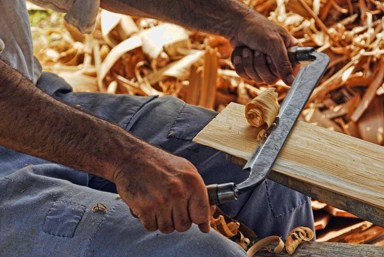 Midsection of man peeling wood at workshop