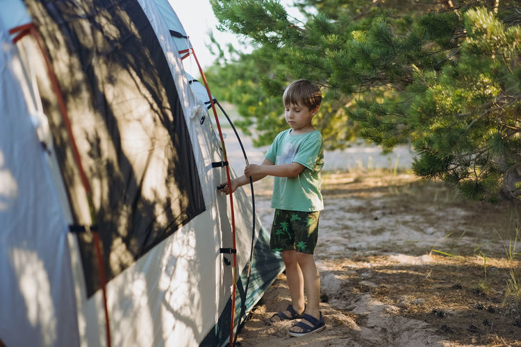 Cute little caucasian boy helping to put up a tent. family camping concept