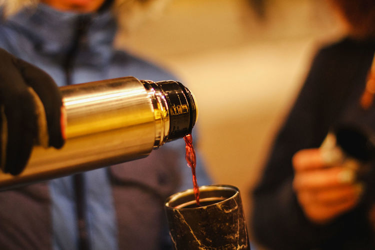 Close-up of hand pouring drink in glass