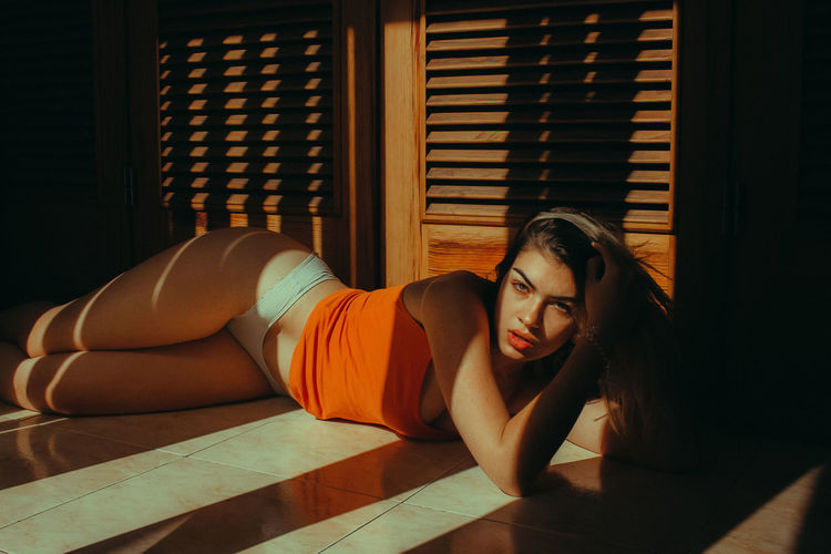 Portrait of sensuous woman lying on floor at home