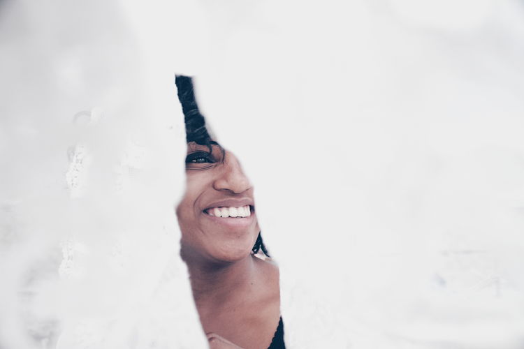 PORTRAIT OF SMILING WOMAN AGAINST WHITE SKY