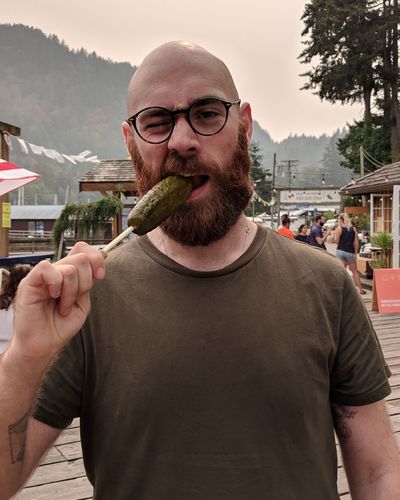 Portrait of young man eating food while standing outdoors