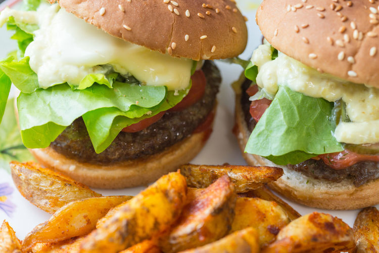 Close-up of burgers and fried potatoes on plate