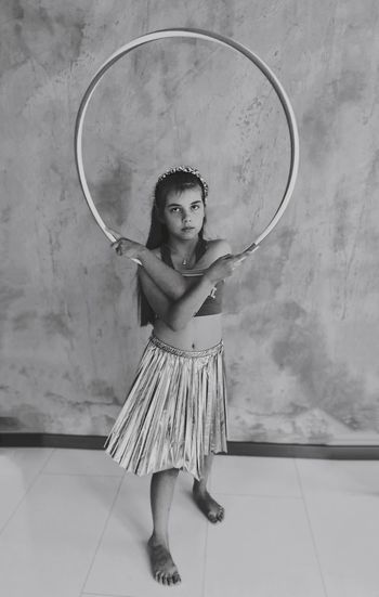 Portrait of girl with plastic hoop standing against wall