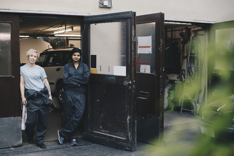 Portrait of female mechanics standing at doorway of auto repair shop