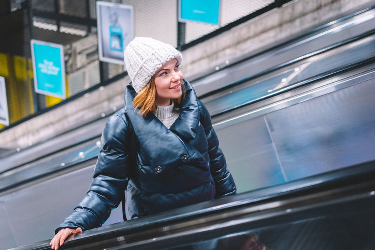 Portrait of smiling woman standing on escalator during winter