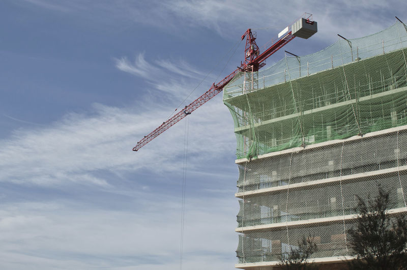 Building under construction with high tolerance crane and blue sky background