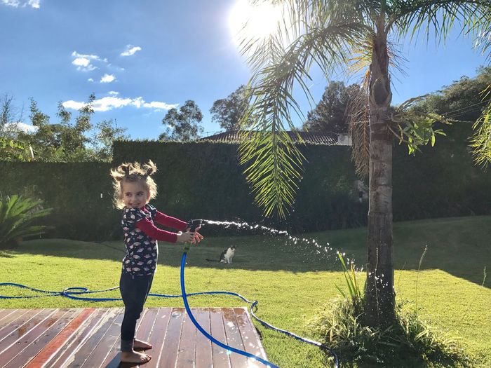 Girl playing with hose in yard