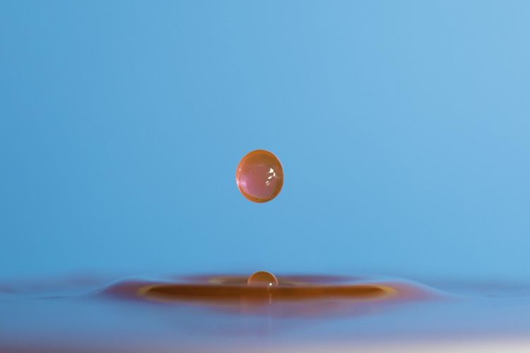 Close-up of water drop against blue sky
