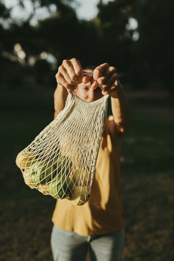 Woman holding fruits in mesh bag