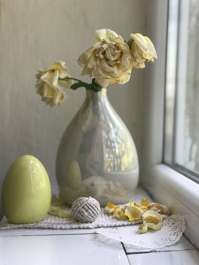 Close-up of white roses in vase on window sill
