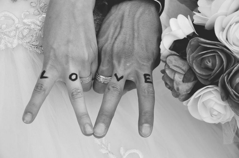 Cropped image of newlywed couple showing love tattoo on fingers