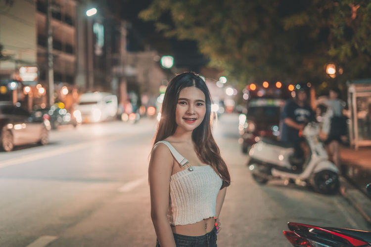 Portrait of smiling woman standing on street in city