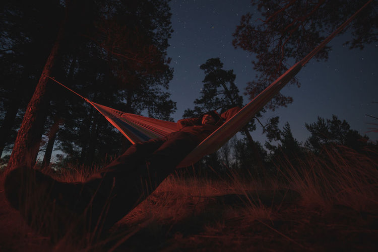 A man sleeps in a hammock in a picturesque place. starlight night. campfire lighting