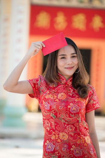 Portrait of a smiling girl standing against red wall