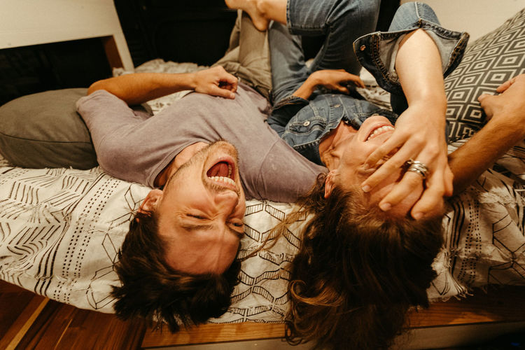 Engaged couple relax and laugh lying upside down on their van bed