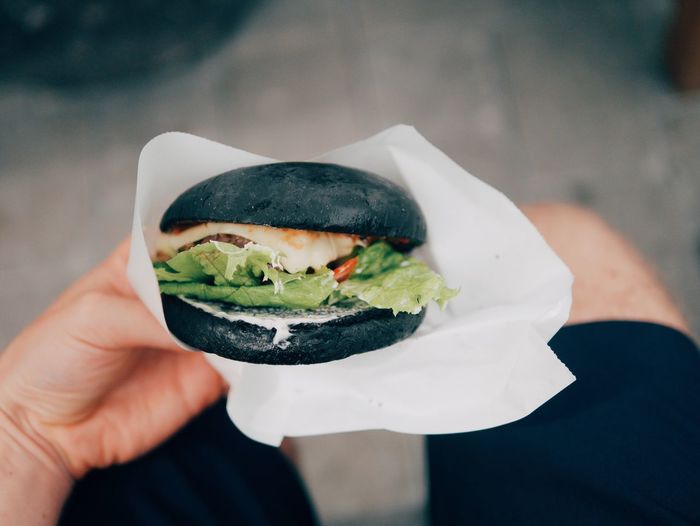 Midsection of man holding black burger