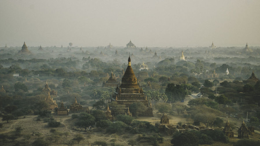 Temples and trees on land against sky