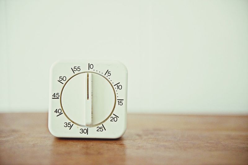 Close-up of oven knob on table against wall