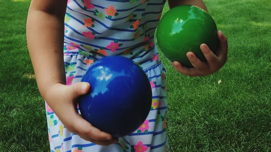 Midsection of girl holding bocce balls while standing at field