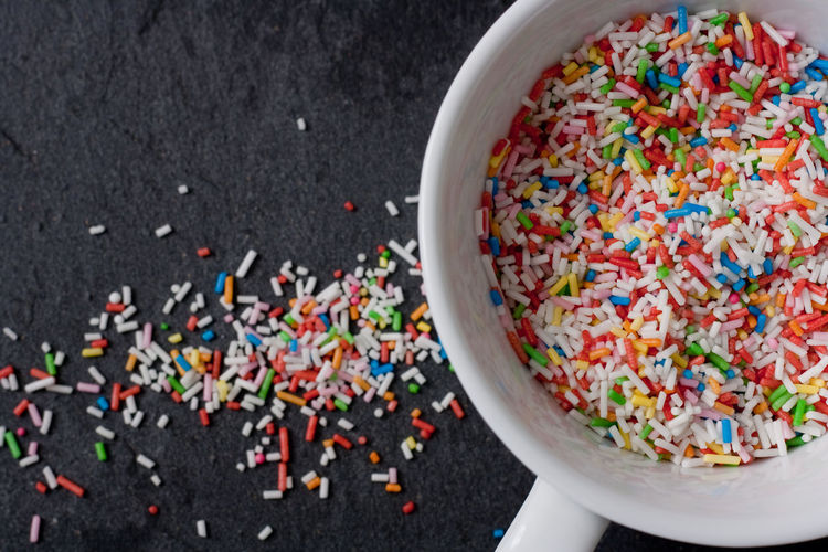 Directly above shot of colorful sprinkles in cup and slate