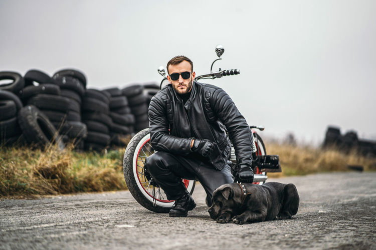 Young man sitting with bicycle on road