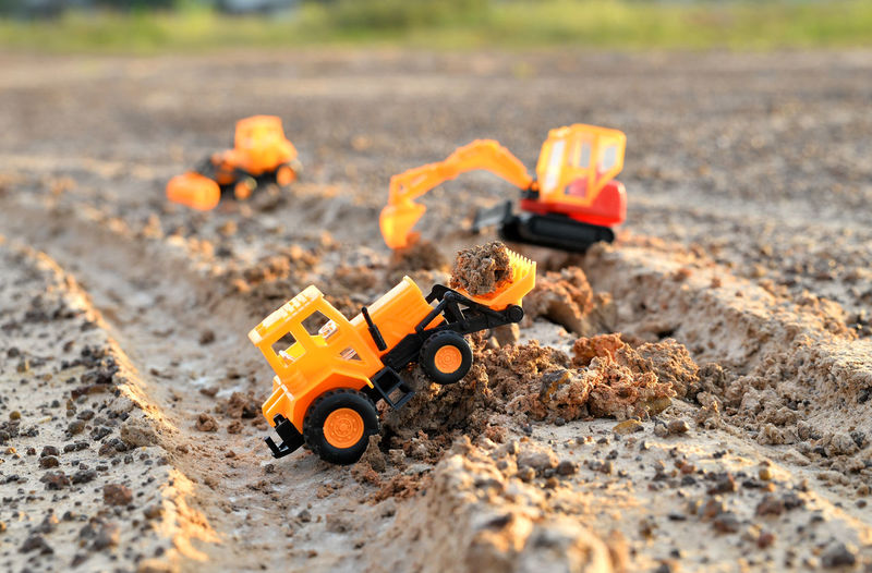 Close-up of toy construction vehicles on dirt