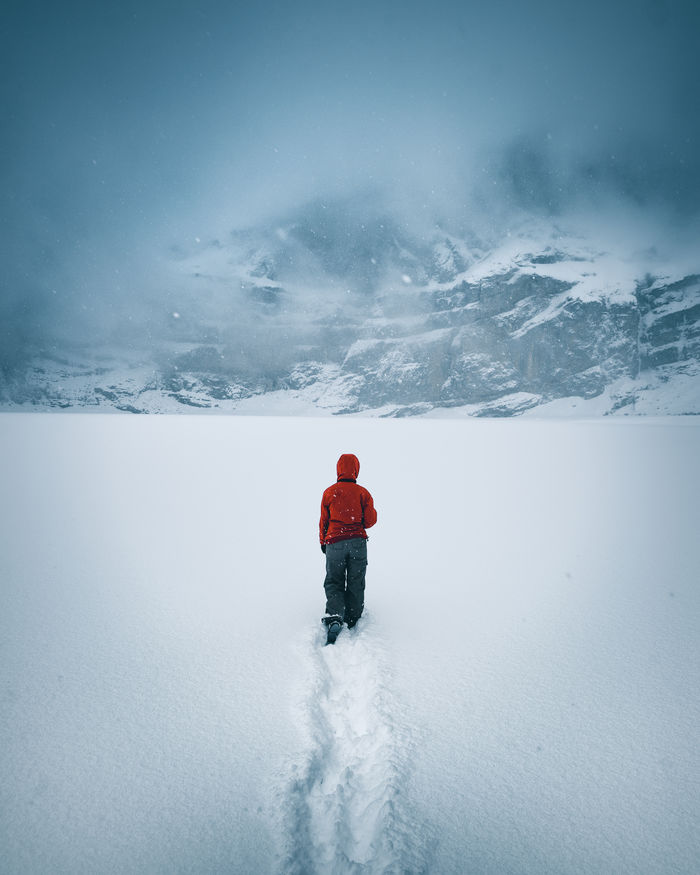 Woman walking on snow covered mountain against sky
