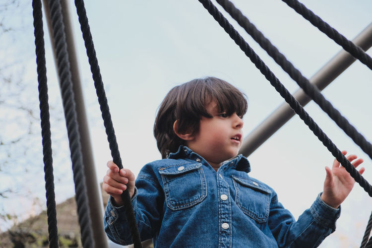 Portrait of young man swinging at playground