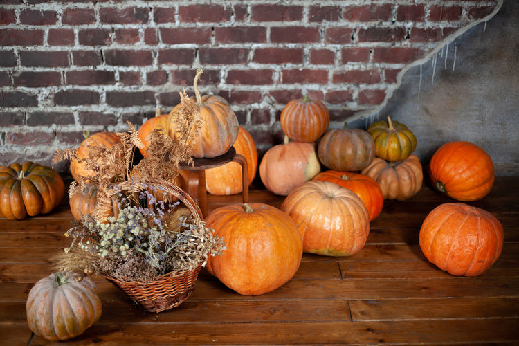 Pumpkins on wooden table against wall during autumn