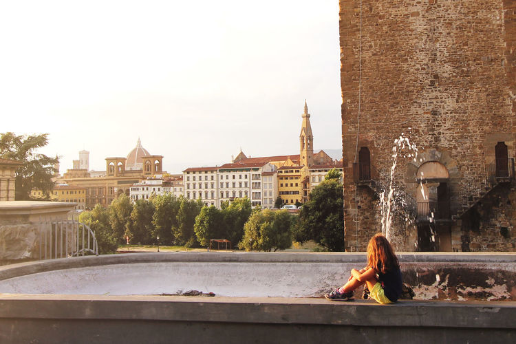 Young girl sitting on the fountain in italian city and enjoing sunset person