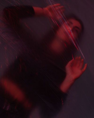 Blurred motion of woman behind plastic in darkroom